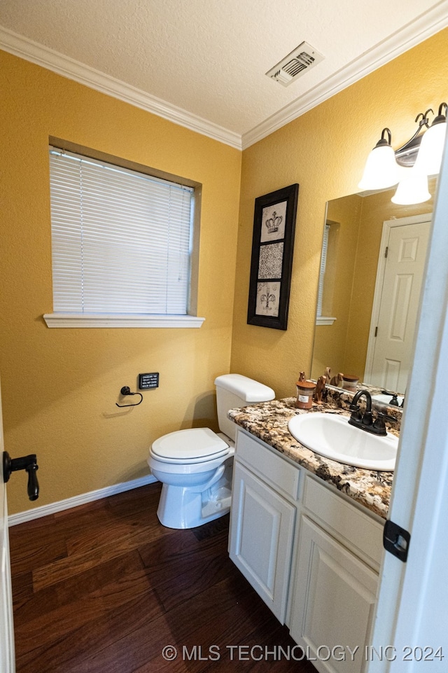 bathroom with vanity, a textured ceiling, crown molding, hardwood / wood-style floors, and toilet