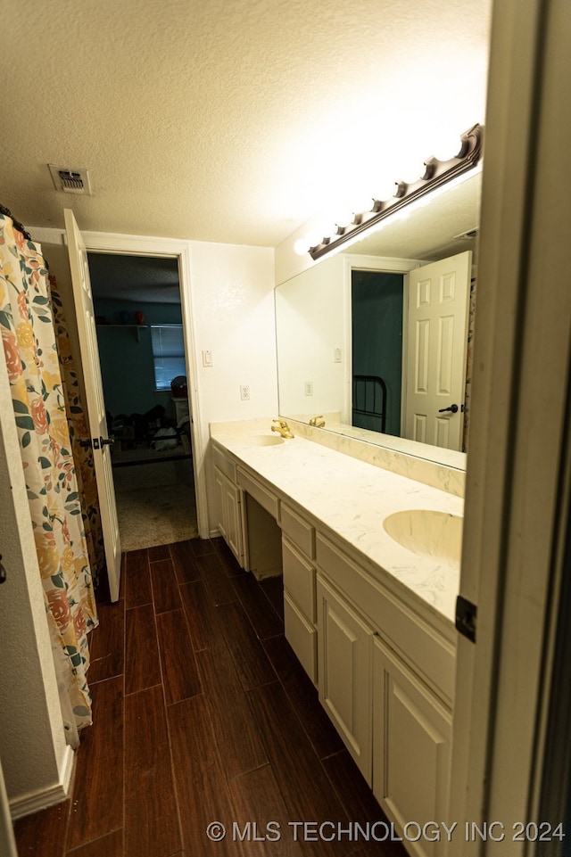 bathroom with hardwood / wood-style floors, vanity, and a textured ceiling