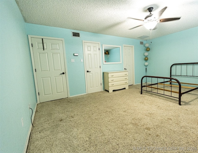 carpeted bedroom featuring ceiling fan and a textured ceiling