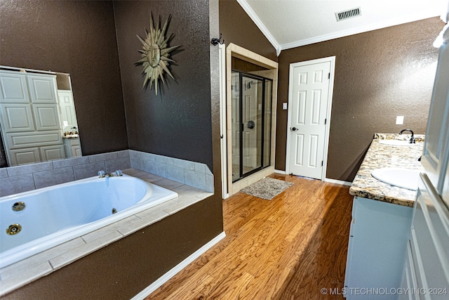 bathroom with vanity, vaulted ceiling, hardwood / wood-style flooring, ornamental molding, and shower with separate bathtub