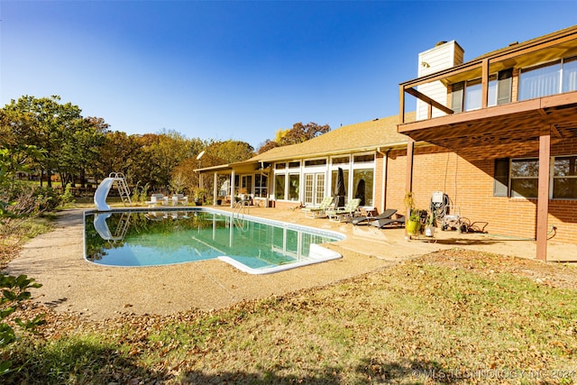 view of pool featuring a water slide and a patio