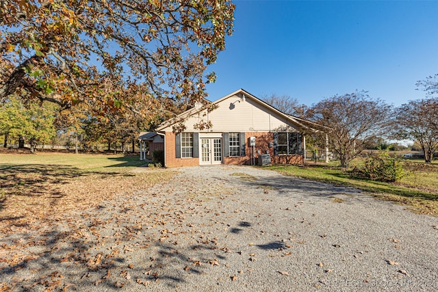 rear view of house with a lawn, cooling unit, and french doors