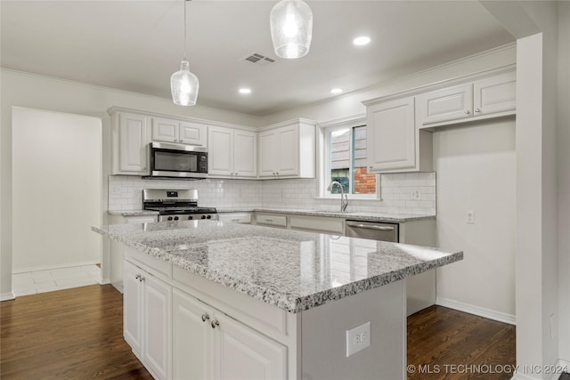 kitchen with stainless steel appliances, dark wood-type flooring, pendant lighting, white cabinets, and a center island