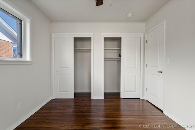 unfurnished bedroom with ceiling fan, dark hardwood / wood-style flooring, ornamental molding, and multiple closets