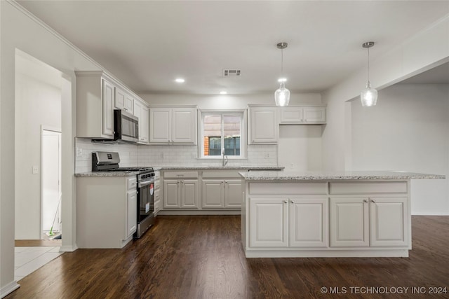 kitchen featuring dark hardwood / wood-style floors, appliances with stainless steel finishes, decorative light fixtures, light stone counters, and white cabinetry