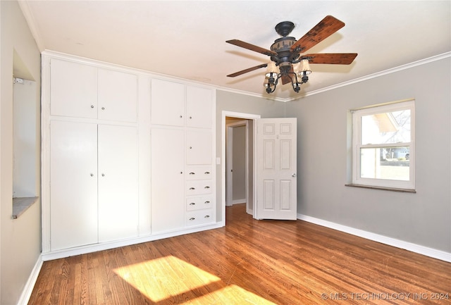 unfurnished bedroom with ceiling fan, a closet, crown molding, and hardwood / wood-style flooring