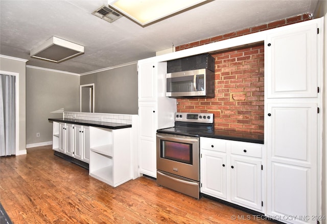 kitchen featuring white cabinets, ornamental molding, stainless steel appliances, and hardwood / wood-style floors