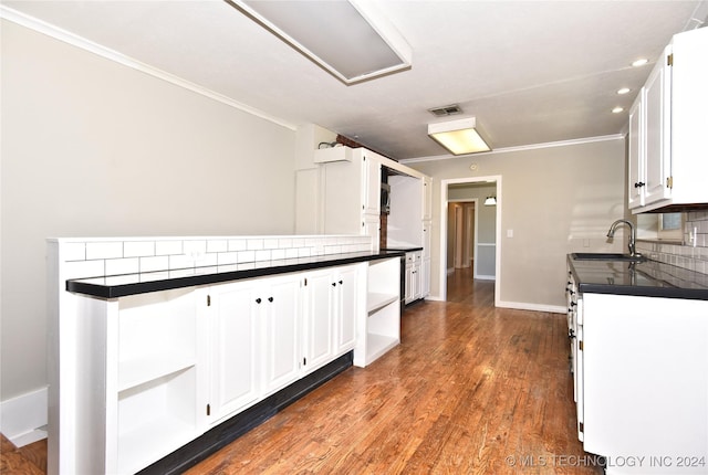 kitchen with tasteful backsplash, sink, white cabinets, and hardwood / wood-style flooring