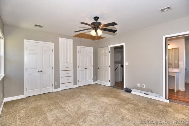 unfurnished bedroom featuring ceiling fan, carpet floors, ensuite bathroom, and two closets