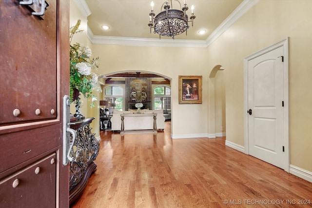 foyer entrance with light hardwood / wood-style flooring, a notable chandelier, and ornamental molding