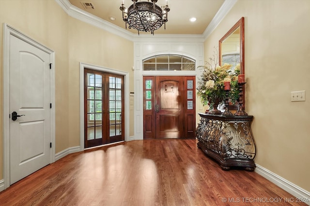 foyer featuring a high ceiling, french doors, hardwood / wood-style flooring, ornamental molding, and a chandelier