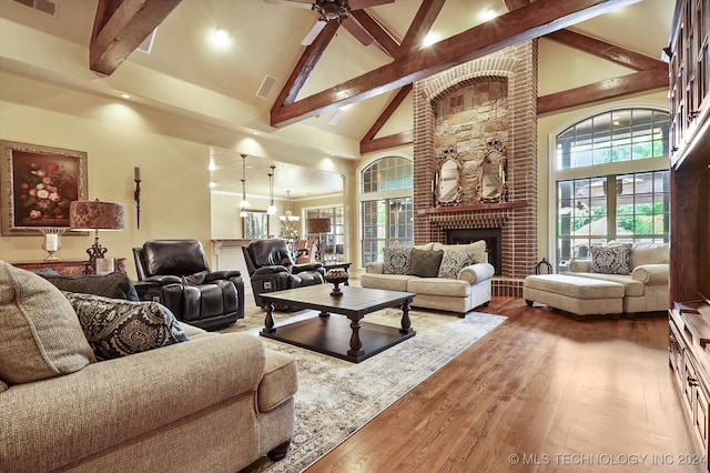 living room with high vaulted ceiling, a brick fireplace, ceiling fan, beam ceiling, and wood-type flooring