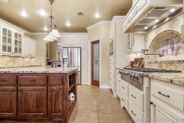 kitchen featuring white cabinets, hanging light fixtures, appliances with stainless steel finishes, tasteful backsplash, and custom range hood