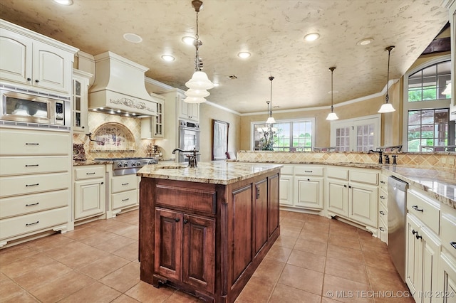 kitchen with a healthy amount of sunlight, pendant lighting, custom range hood, and appliances with stainless steel finishes