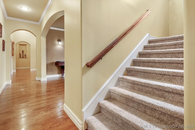 stairway with ornamental molding and hardwood / wood-style flooring