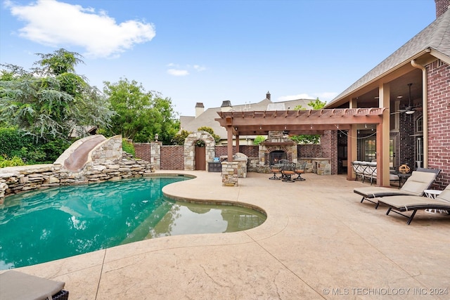 view of pool with a water slide, a pergola, an outdoor stone fireplace, ceiling fan, and a patio