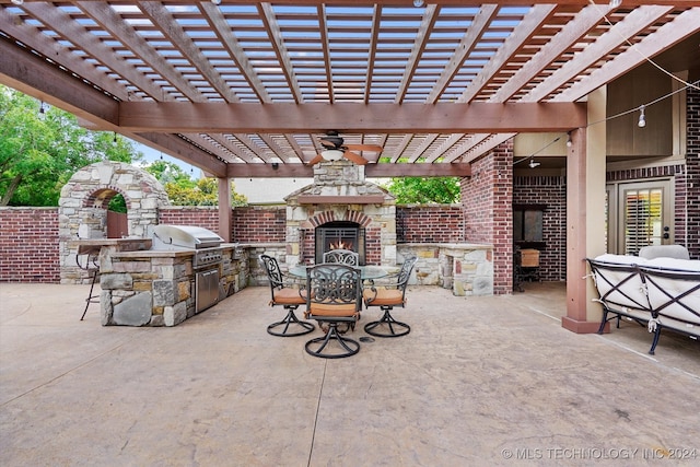 view of patio with ceiling fan, exterior kitchen, a pergola, an outdoor stone fireplace, and grilling area