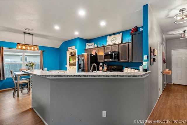 kitchen with decorative light fixtures, stainless steel appliances, light hardwood / wood-style flooring, and light stone counters