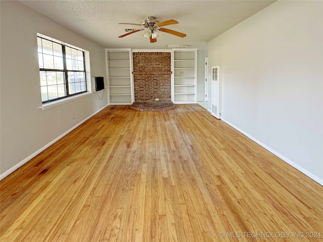 unfurnished living room featuring a fireplace, a textured ceiling, light wood-type flooring, and ceiling fan