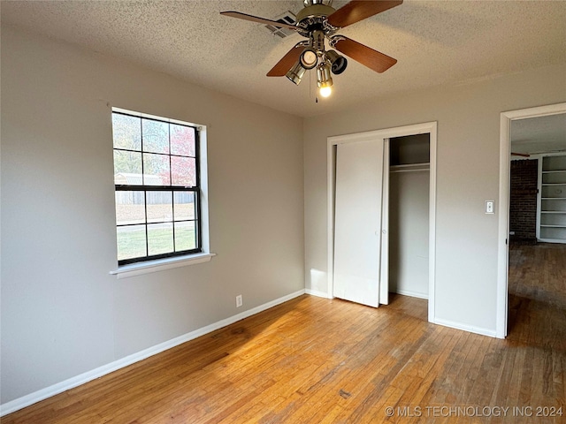 unfurnished bedroom featuring ceiling fan, a closet, a textured ceiling, and light wood-type flooring