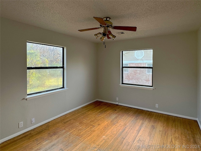 unfurnished room with light hardwood / wood-style floors, a textured ceiling, and a wealth of natural light