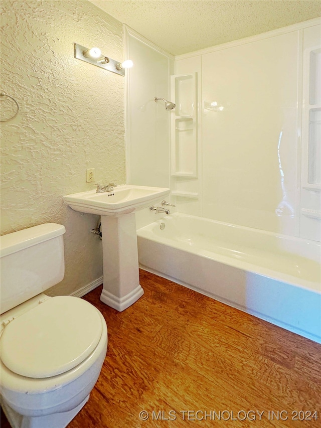 bathroom featuring toilet, hardwood / wood-style floors, a textured ceiling, and bathtub / shower combination