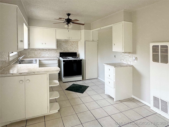 kitchen with tasteful backsplash, white cabinetry, white gas stove, and sink