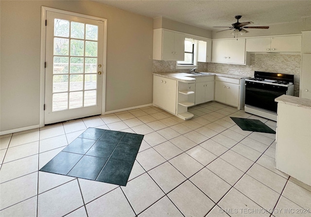 kitchen with decorative backsplash, gas range gas stove, ceiling fan, white cabinets, and light tile patterned flooring