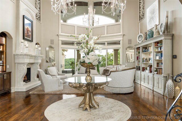 living area featuring a notable chandelier, dark hardwood / wood-style flooring, and a high ceiling