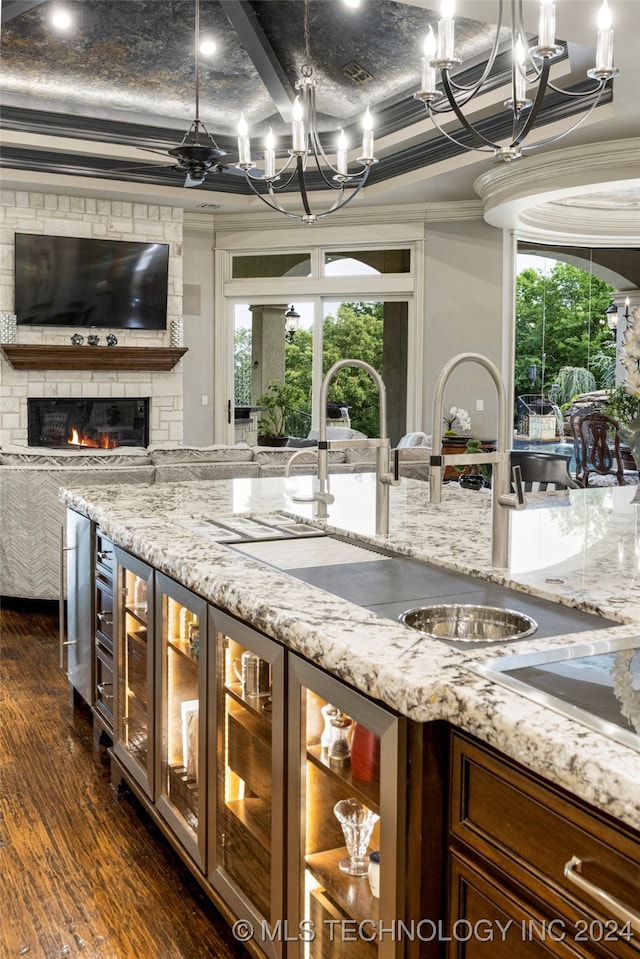 kitchen with dark hardwood / wood-style flooring, crown molding, sink, a fireplace, and a chandelier