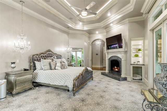 carpeted bedroom featuring ceiling fan, a premium fireplace, crown molding, and a high ceiling