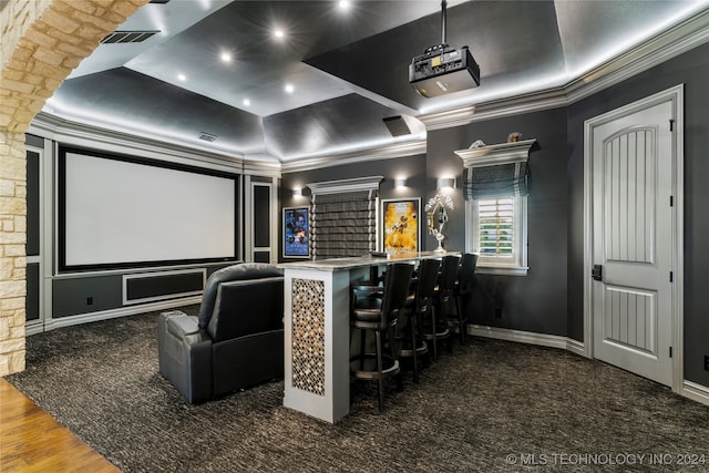 home theater featuring dark hardwood / wood-style floors, ornamental molding, and bar