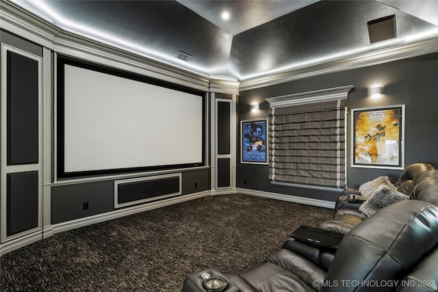 carpeted home theater room with crown molding and vaulted ceiling