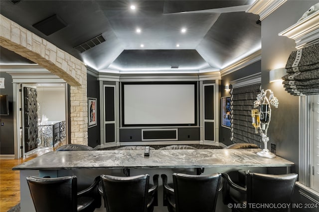 home theater room with hardwood / wood-style floors, a tray ceiling, and ornamental molding