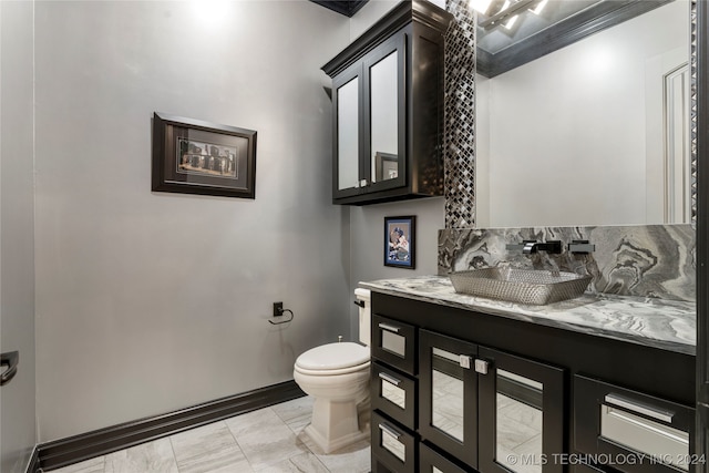 bathroom with toilet, vanity, and ornamental molding