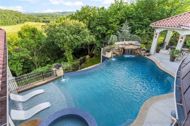 view of swimming pool featuring pool water feature, a patio area, and an in ground hot tub