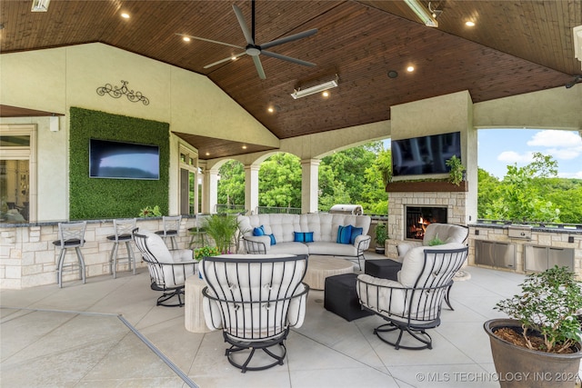 view of patio / terrace with an outdoor living space with a fireplace, an outdoor kitchen, an outdoor bar, and ceiling fan