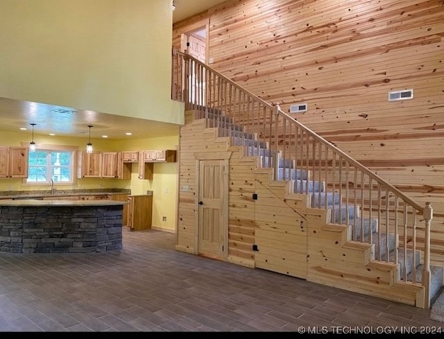 stairway featuring hardwood / wood-style flooring, wooden walls, sink, and a high ceiling