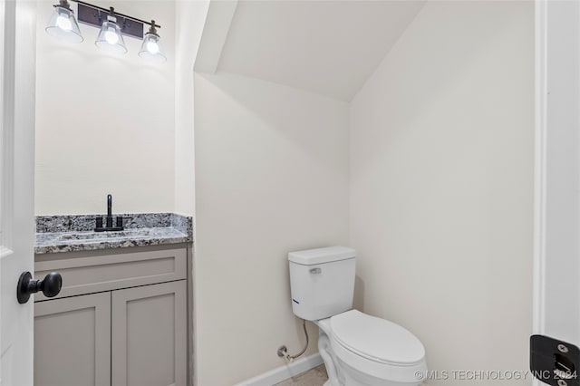 bathroom with vanity, toilet, and vaulted ceiling