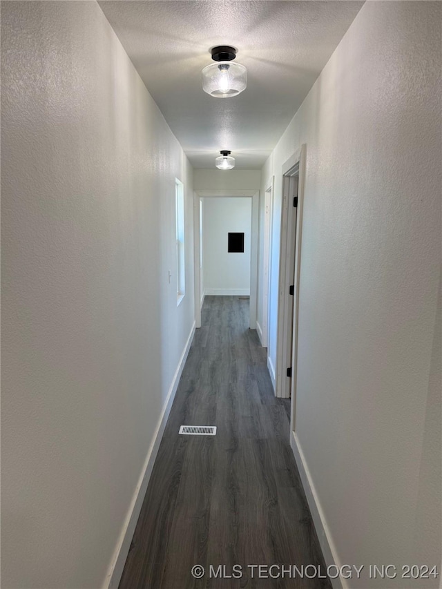 hallway featuring dark hardwood / wood-style floors and a textured ceiling