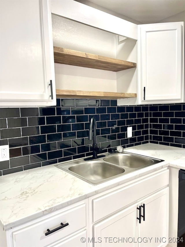 kitchen featuring tasteful backsplash, light stone countertops, sink, and white cabinets