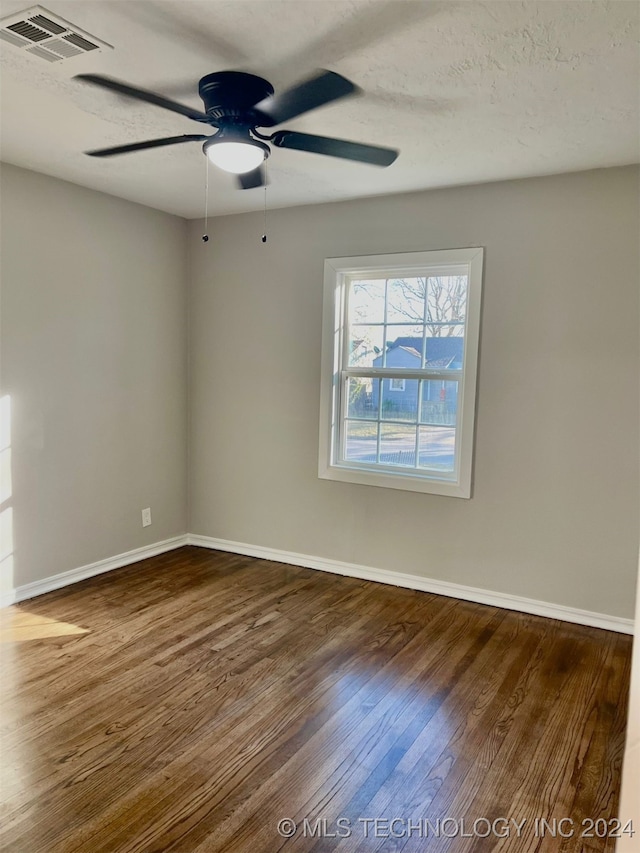 empty room featuring dark wood-type flooring, ceiling fan, and a textured ceiling