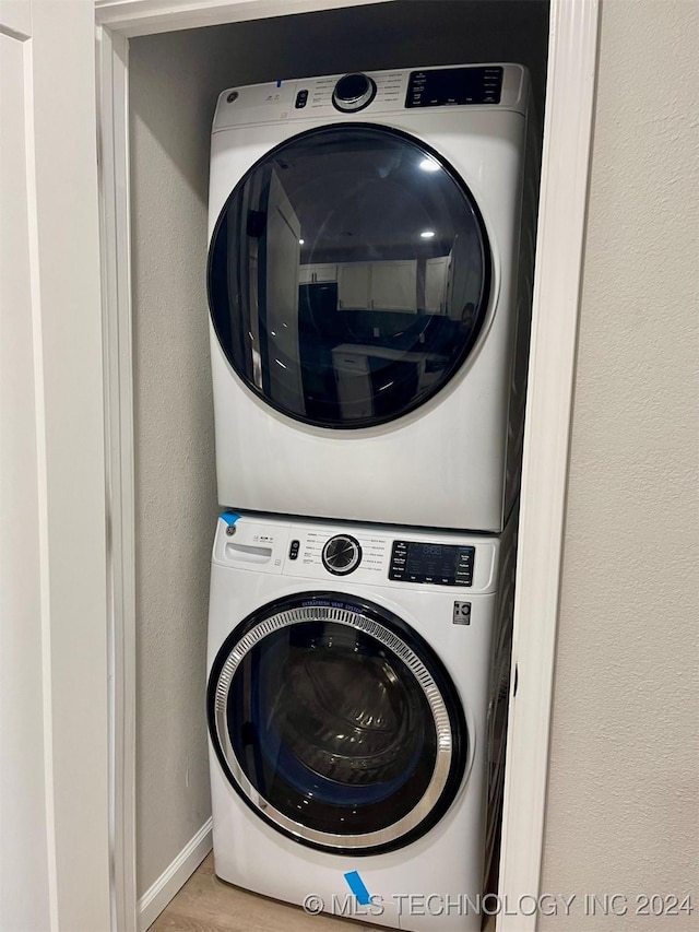 clothes washing area with light hardwood / wood-style flooring and stacked washer / dryer