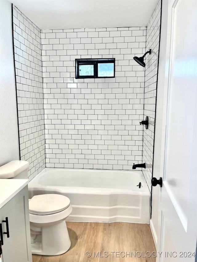 full bathroom featuring vanity, tiled shower / bath, hardwood / wood-style floors, and toilet