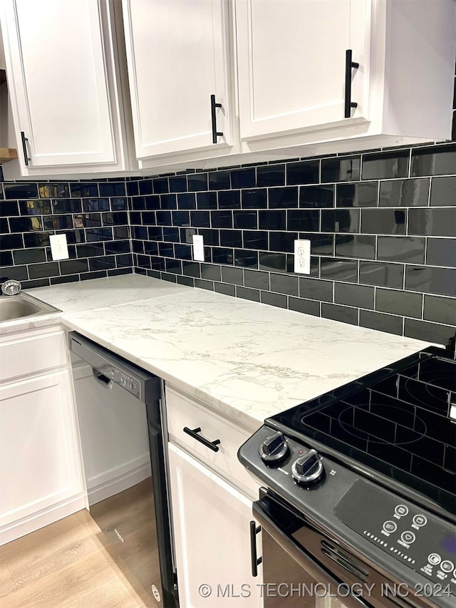 kitchen featuring white cabinets, backsplash, light stone counters, black appliances, and light wood-type flooring