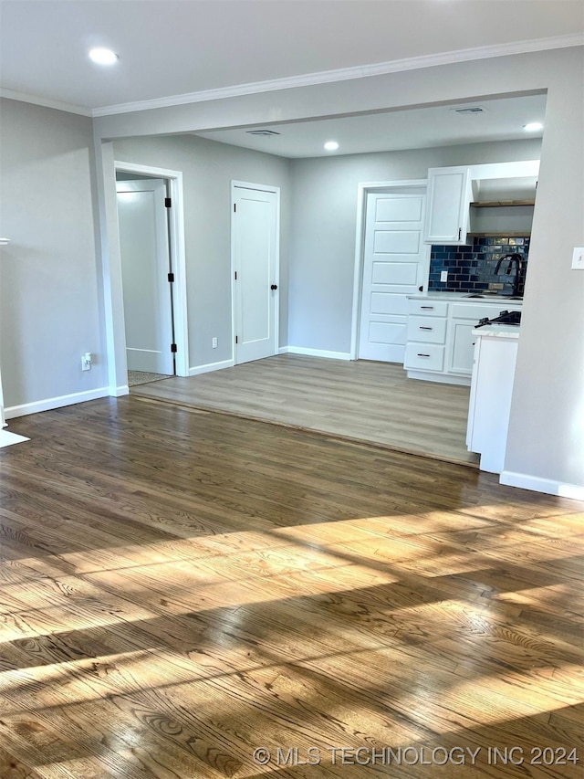 unfurnished living room featuring sink, ornamental molding, and dark hardwood / wood-style floors