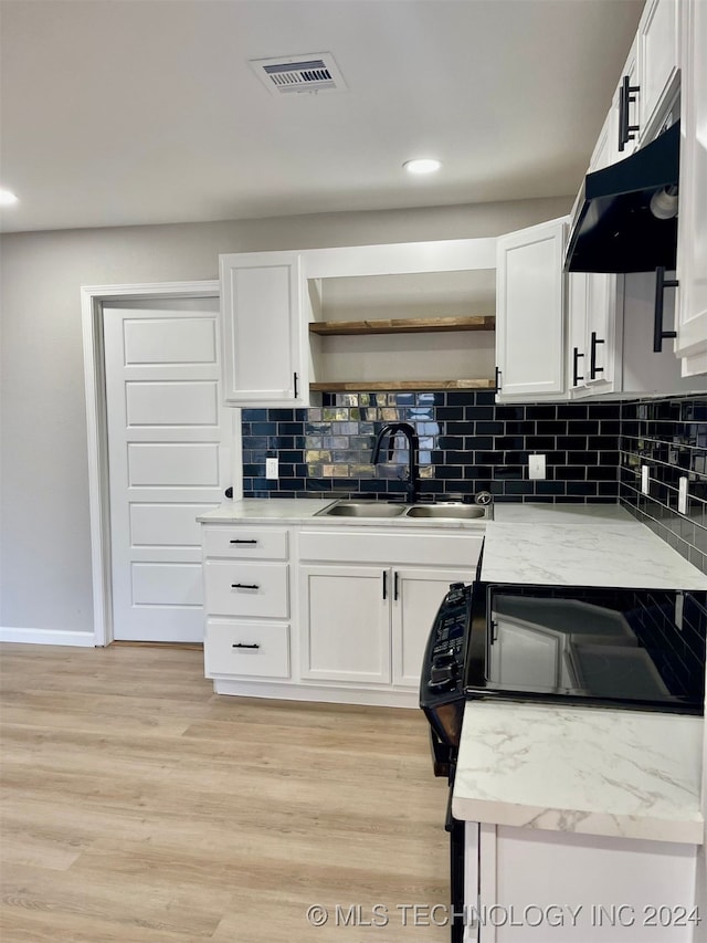 kitchen featuring backsplash, light hardwood / wood-style floors, sink, and white cabinets