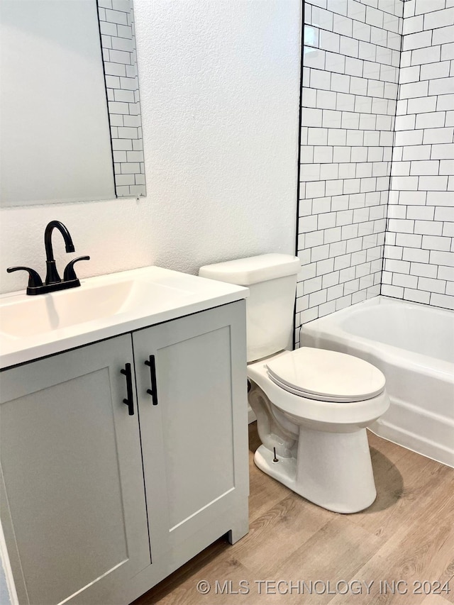 full bathroom with vanity, hardwood / wood-style floors, tiled shower / bath, and toilet