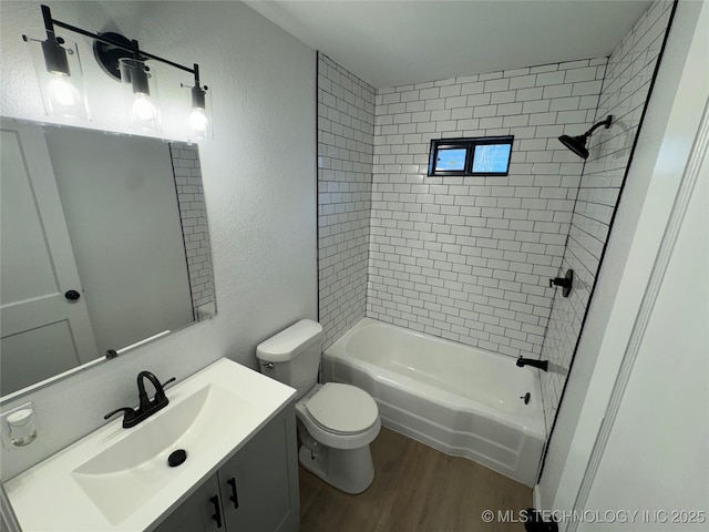 full bathroom featuring hardwood / wood-style flooring, vanity, tiled shower / bath combo, and toilet