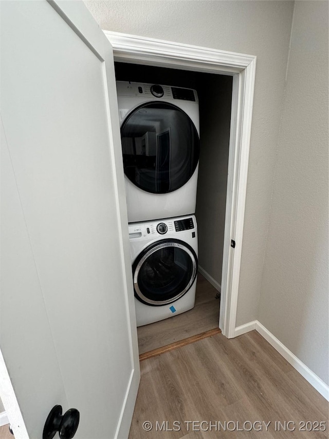 laundry room with stacked washing maching and dryer and hardwood / wood-style floors